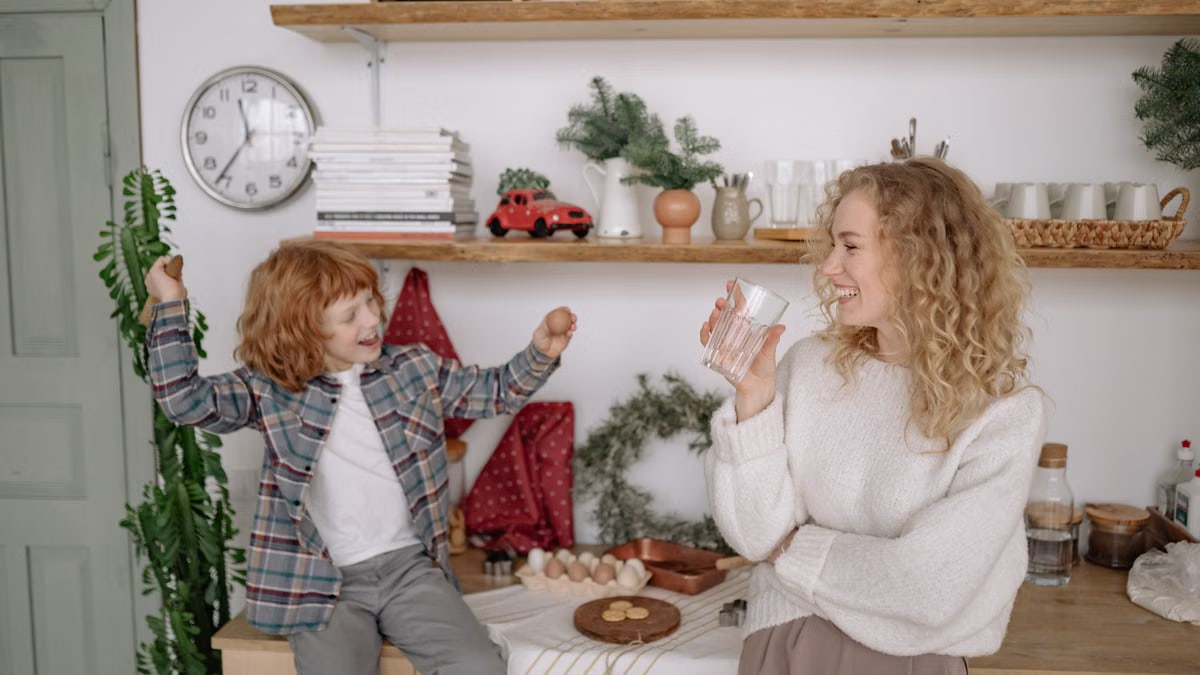 A cheerful mother and her excited son bond while cooking together in a cozy kitchen setting.